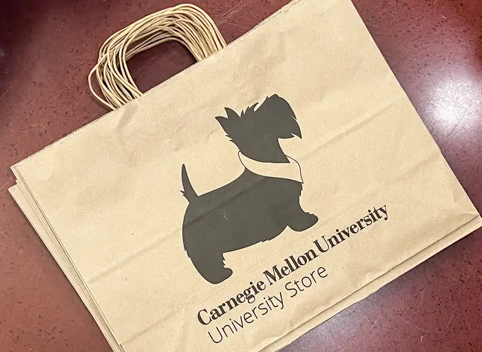 a paper bag with a CMU Scotty dog printed on it. The text reads "Carnegie Mellon University University Store."