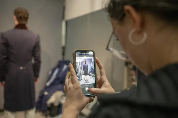 Costume design student uses phone to take photo of actore wearing a costume in progress