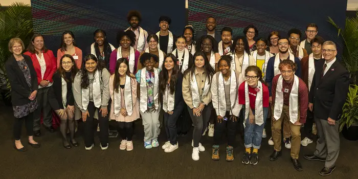 a group of graduates wearing their stoles pose with speakers from the event