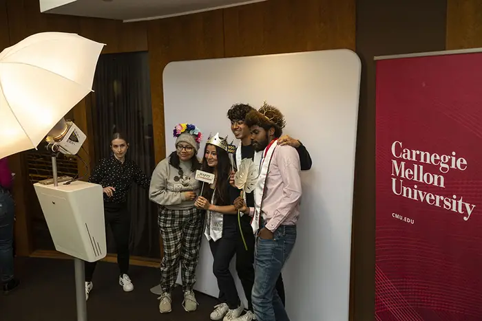 small group of students wearing fun hats and posing in a photo booth