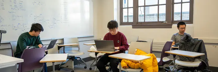 three students seated in classroom