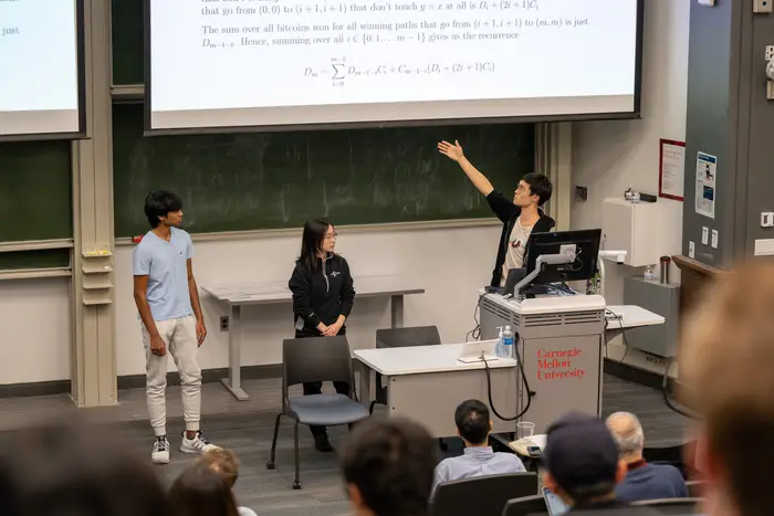 three students presenting at front of classroom