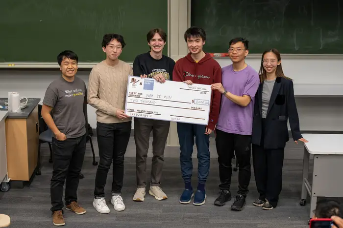 Six students holding large check at front of classroom