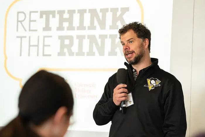 Tyler Kennedy standing speaking into microphone