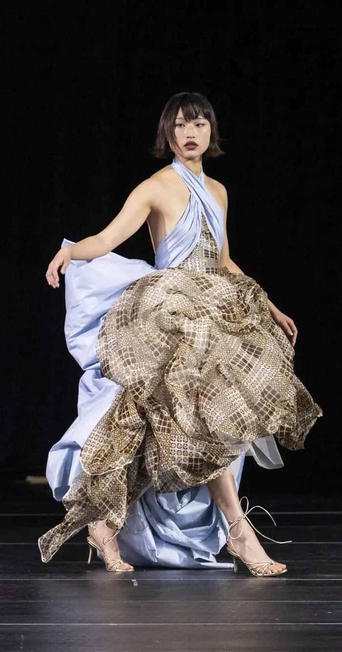 Model wearing voluminous periwinkle dress with sparkly brown layered fabric.