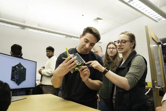 Colton Amos discusses the intricacies of cube satellite technology with Ashley Kline during demonstration day.