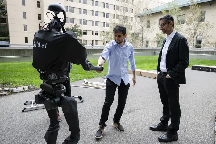Professor Deepak Pathak, Raj Reddy Assistant Professor in Robotics and co-founder and CEO of Skild AI (left) show Pichai some robots at CMU.