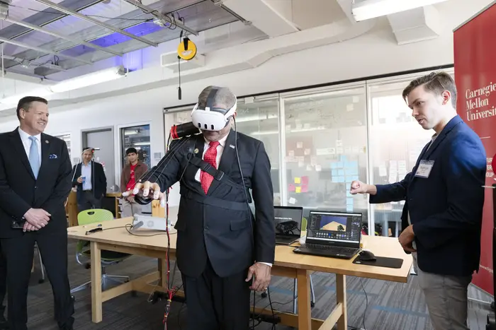 Sethuraman Panchanathan wearing VR headset and sensing tech on his hand while others look on