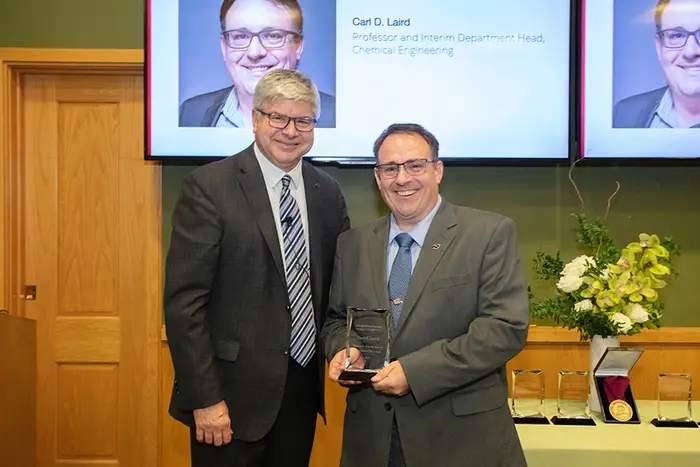 Carl Laird, with Dean Bill Sanders, receives the 2024 Steven J. Fenves Award for Systems Research from the College of Engineering.