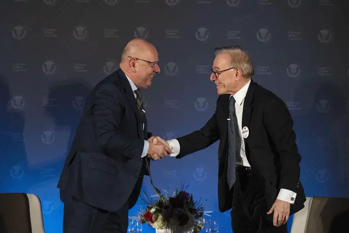 Farnam Jahanian and David Ignatius shake hands. 
