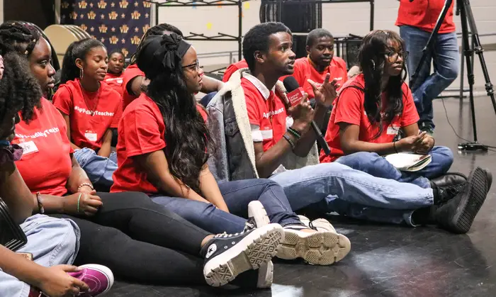 Students ask questions in a theater during the master class. 