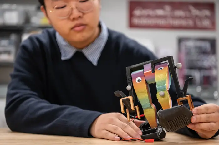 Ben Gu holding small biped robot