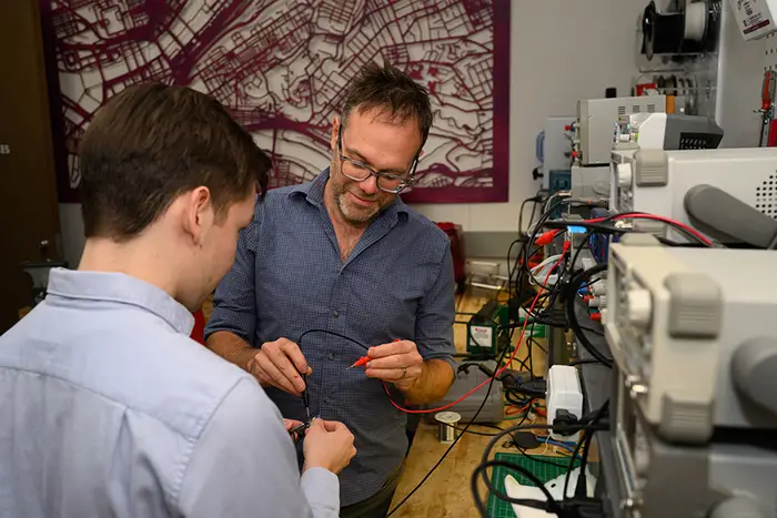 Chris Harrison works with a student to connect electrical wires