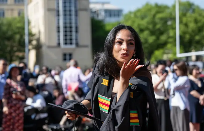 A graduate blows a kiss to her family in the audience during the procession.