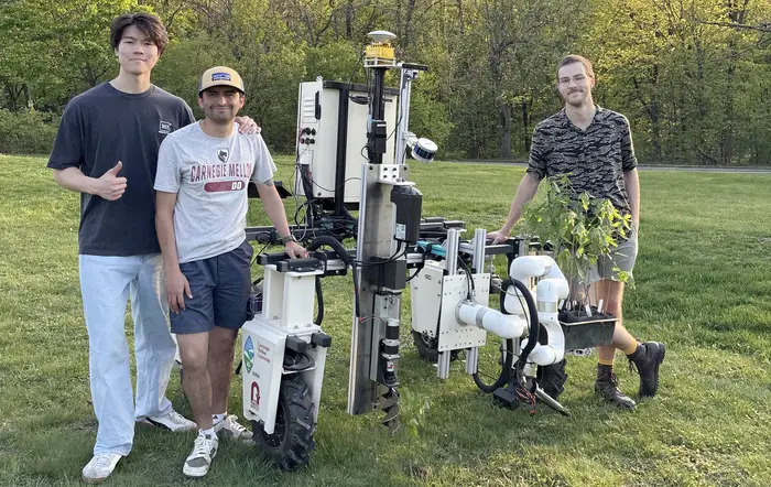 Three students stand next to a robot. 