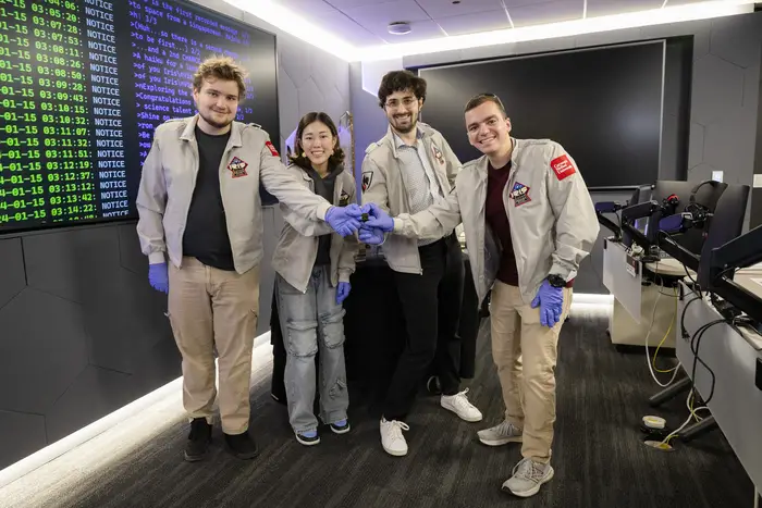 The team holds a small piece of the payload headed for the moon.