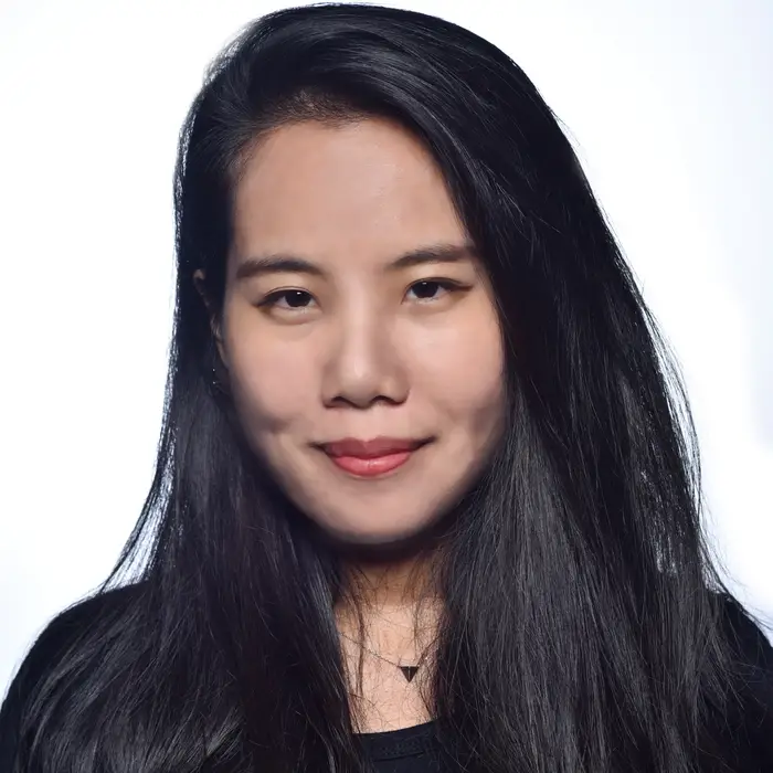 A woman with long black hair and red lipstick smiles at the camera