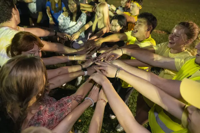 A group of CMU first-year students put their hands together.