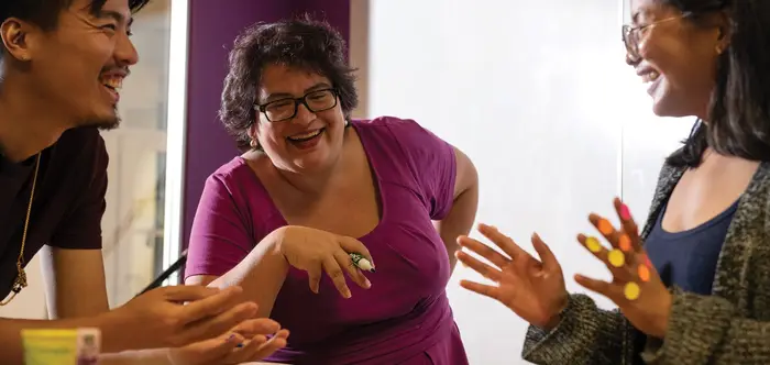Three people talk while smiling. 