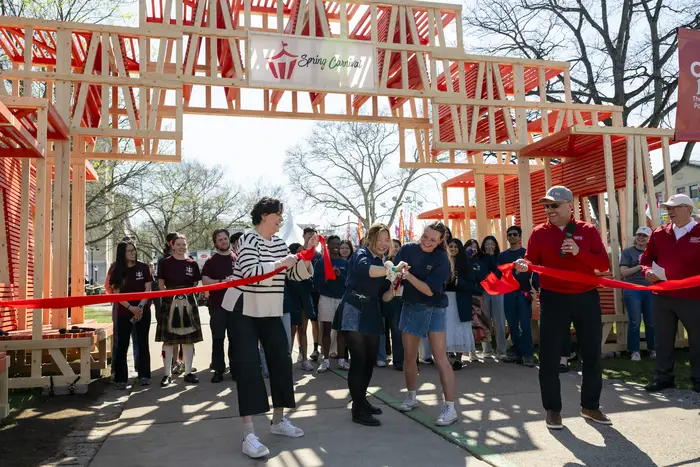A group of people cut a ribbon opening Carnival 2026. 