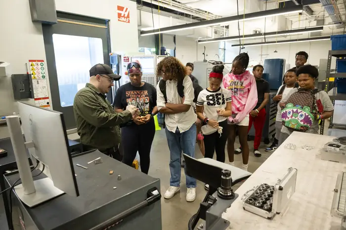 Technician explaining equipment to middle schoolers in lab