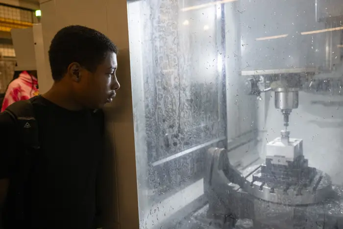 Student watches manufacturing process through window