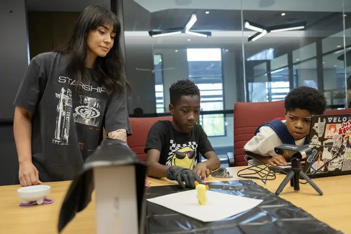 CMU student advises two middle schoolers at a table