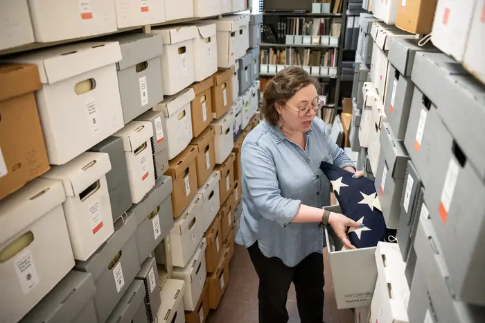 Julia Corrin pulls a flag from a box in the University Archives.