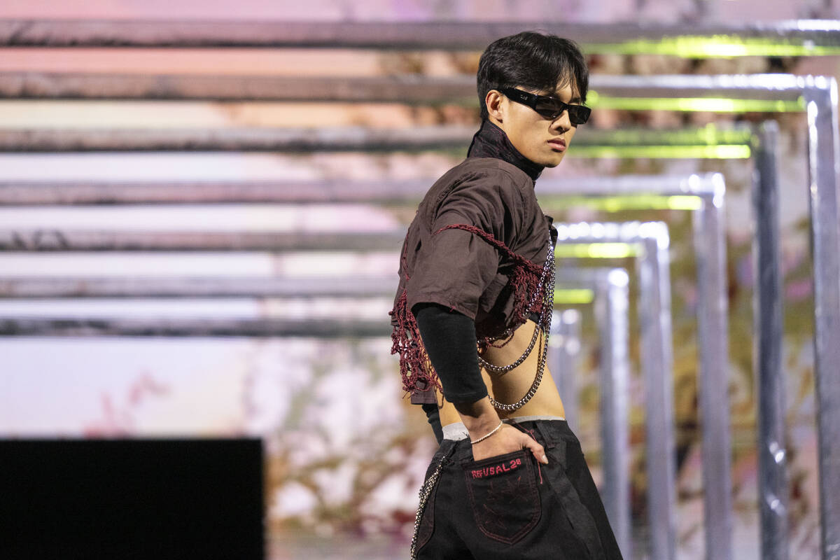 Male model wearing red embroidered crop top with chains and sunglasses. 