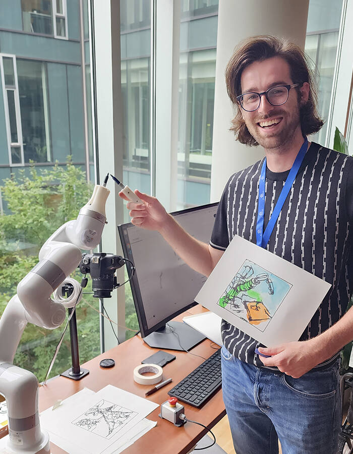 Peter Schaldenbrand, a Ph.D. student in the Robotics Institute at Carnegie Mellon University’s Robotics Institute, poses next to CoFRIDA with a portrait of the robot he created with the collaborative painting system.