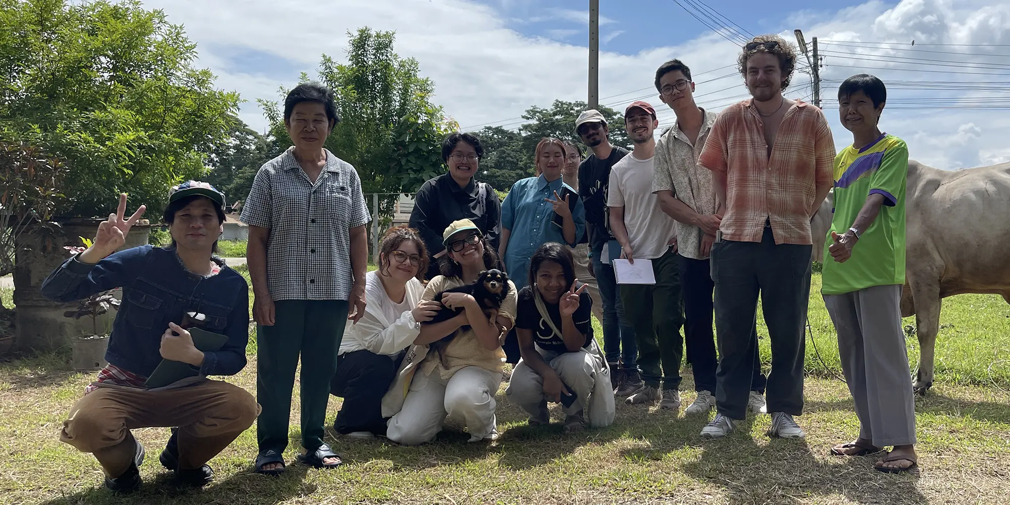 students pose with two elders and animals outdoors