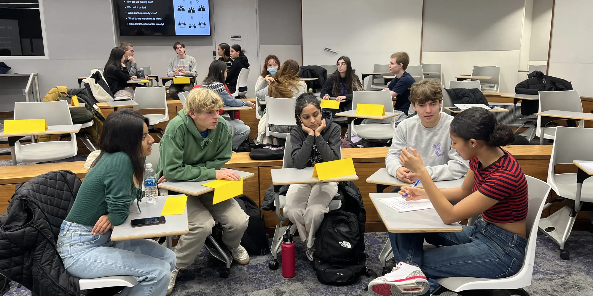 view of classroom focused on five students seated at their desks in a semicircle