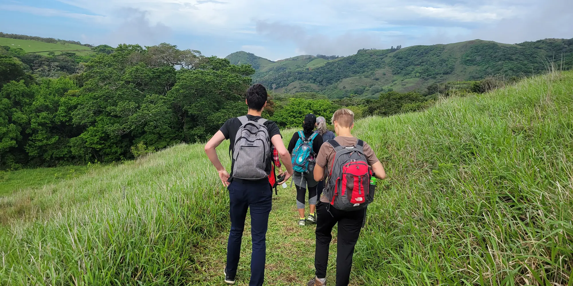 People walking on a green hill's path in Costa Rica.