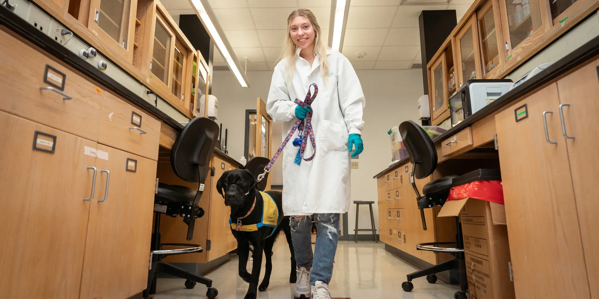 Kara Mathias works in the lab alongside a dog she is training to be a service animal.