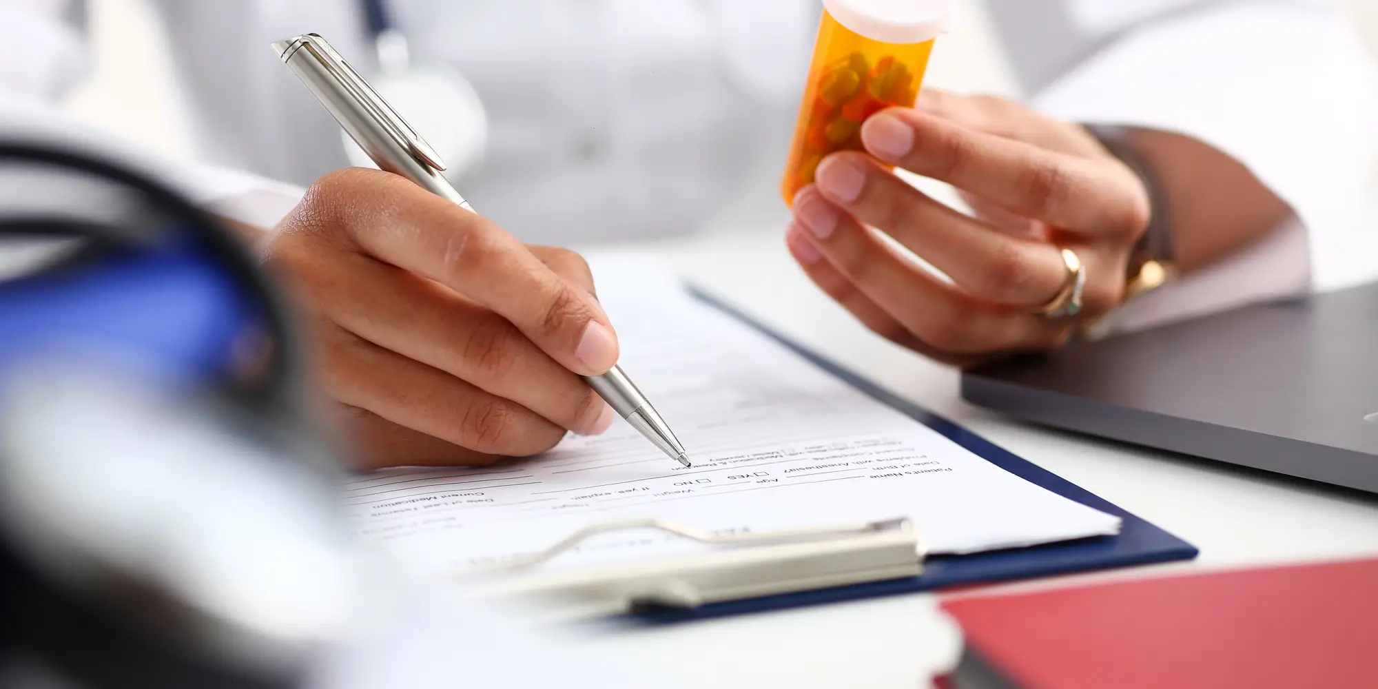 Physician holding a pill bottle, writing a note