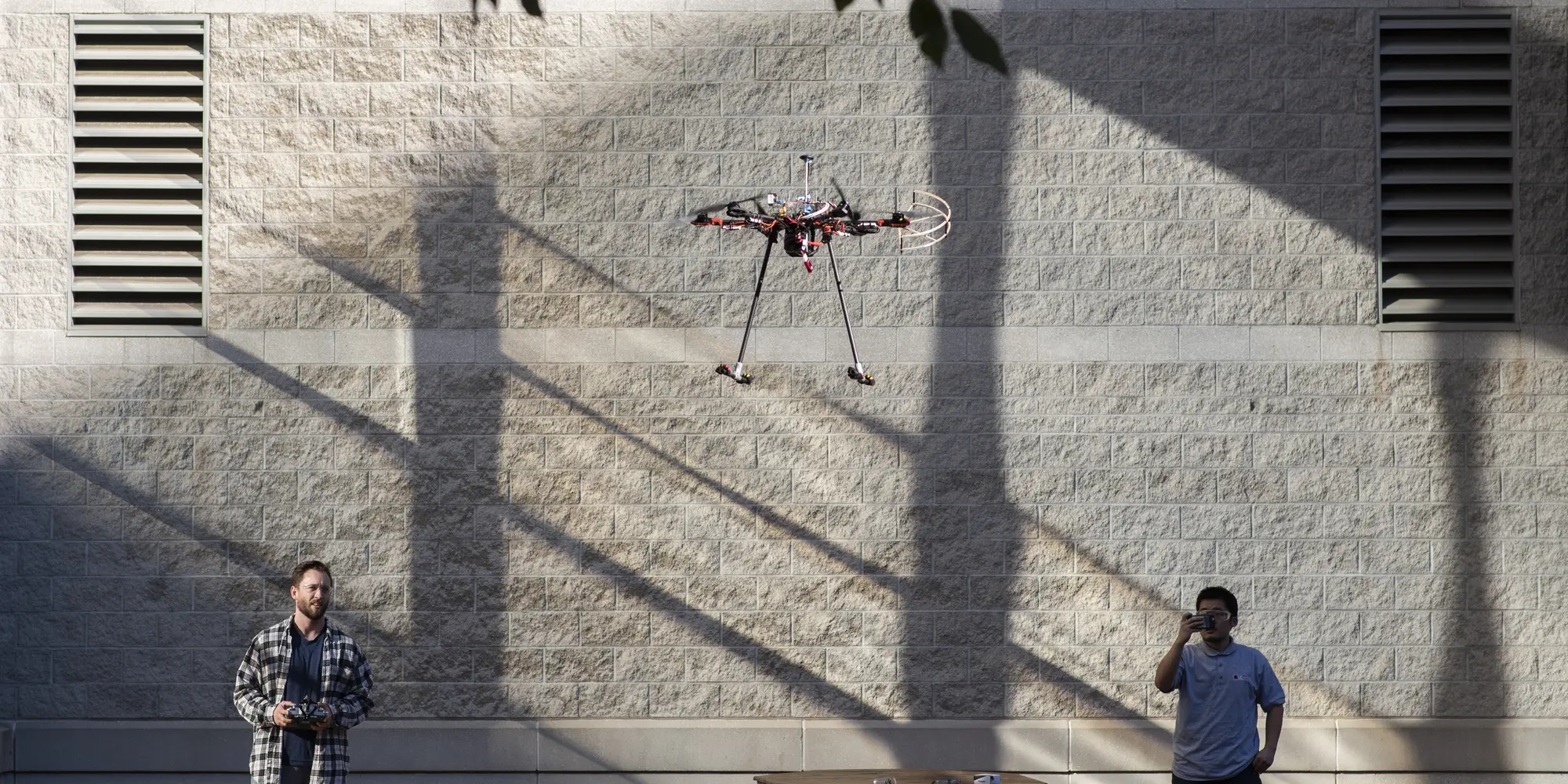 Two students fly a drone. 