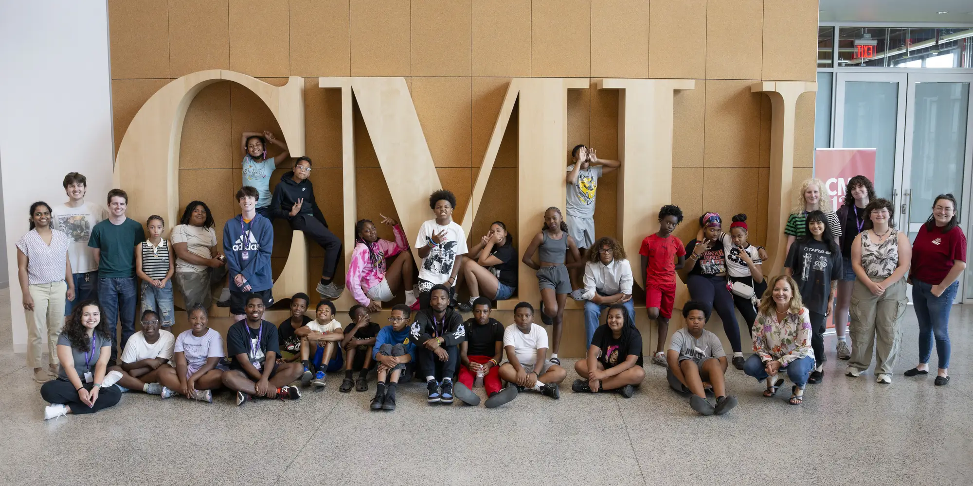 students standing in front of large wooden CMU letters
