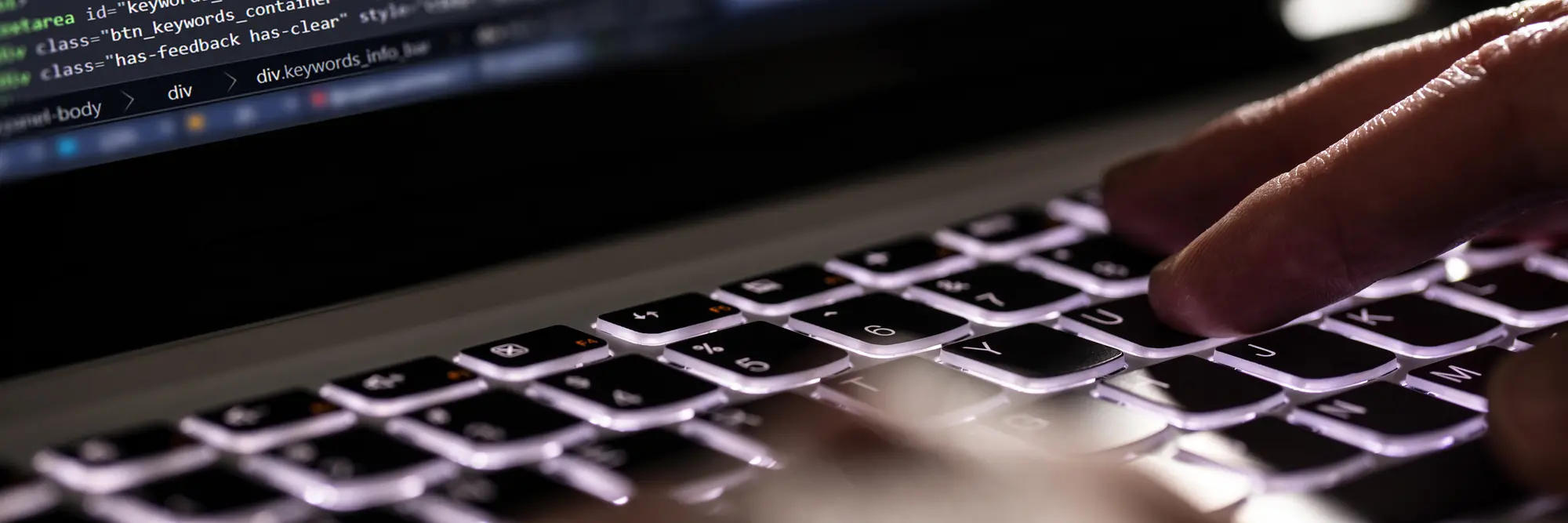 A close up of hands typing computer code on a keyboard.