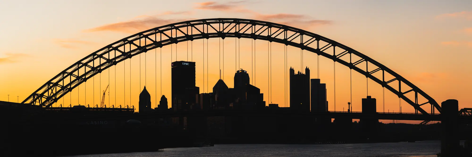 The city of Pittsburgh, seen silhouetted through a bridge. 