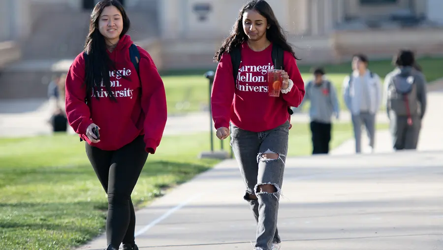 two girls in red CMU hoodies walking on campus