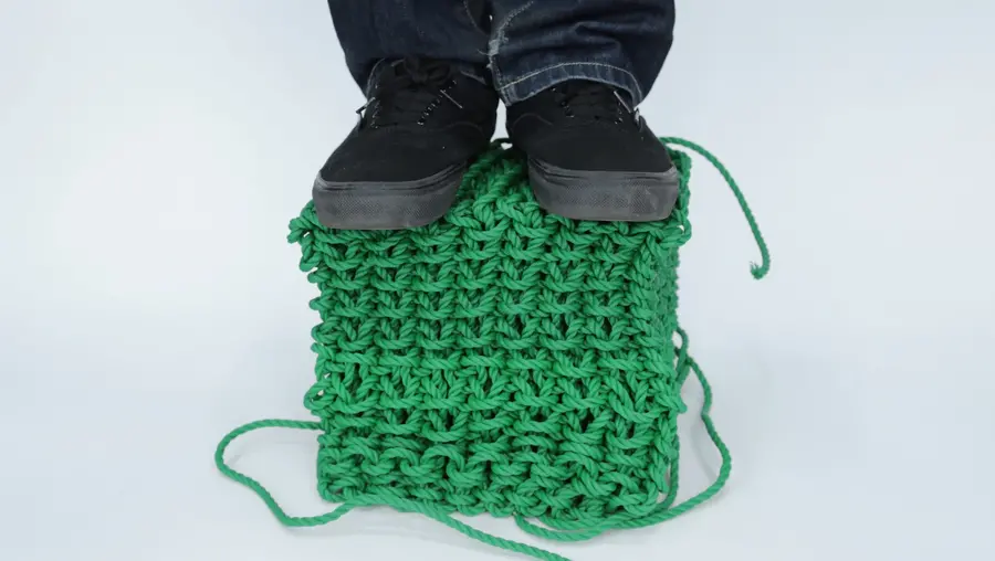 A person stands on a knitted cube made with a new fabrication technique.