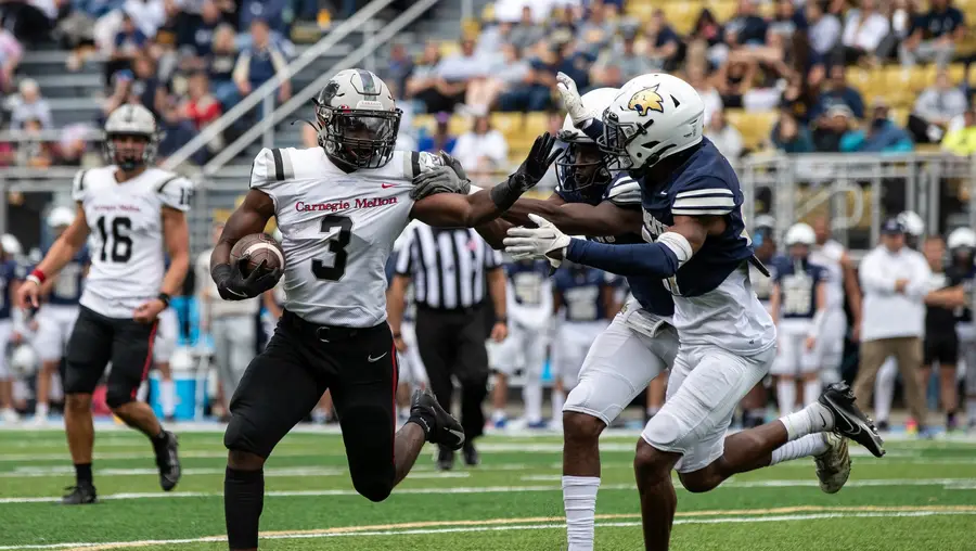 A running back in football pushes back against defenders.