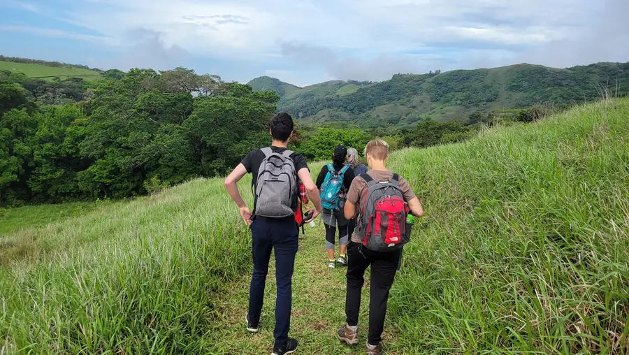 People walking on a green hill's path in Costa Rica.