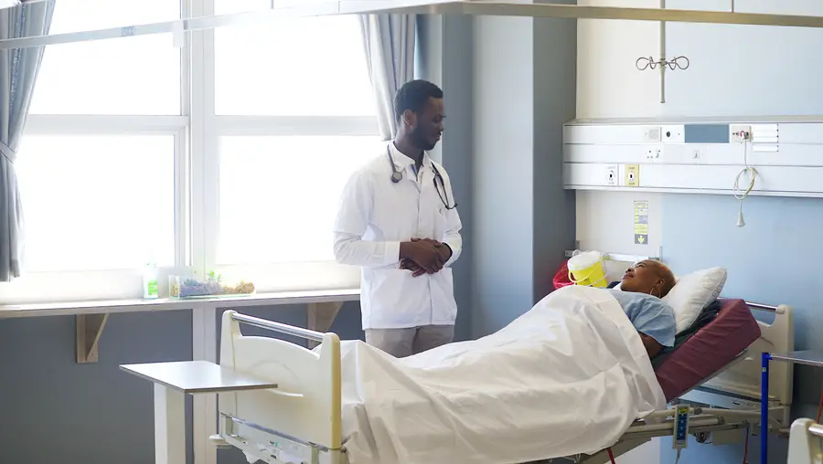 Black patient in a hospital bed, speaking to a doctor