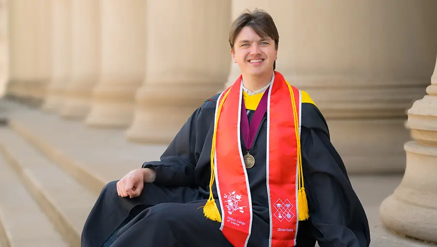graduate in gown seated on Mellon Institute steps