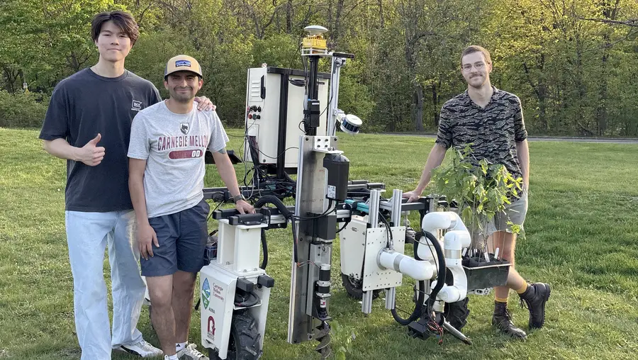 Three students stand next to a robot.