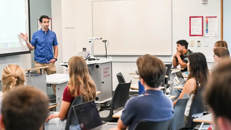 A group of students listen to an instructor at class. 