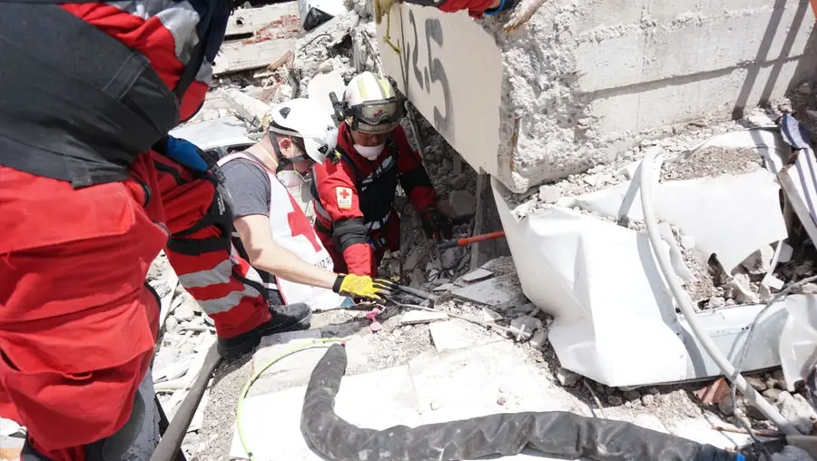 The Robotics Institute’s Matt Travers, center, in white vest, works with red-suited Mexican Red Cross workers to prepare a snake robot to enter a collapsed apartment building in Mexico City.