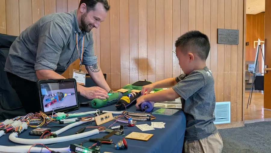 IDeATe Technical Specialist Cody Soska helps a young learner investigate the brightly colored neuron, lit with LEDs