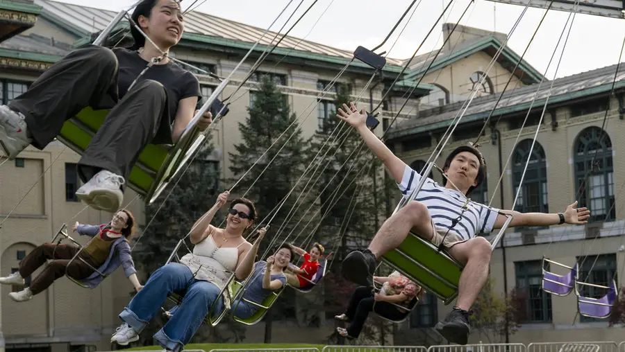 Students ride a carnival swing ride. 